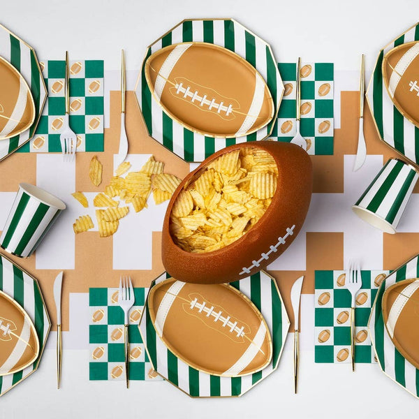 Football themed table with green checker napkins, plates, and game day snacks
