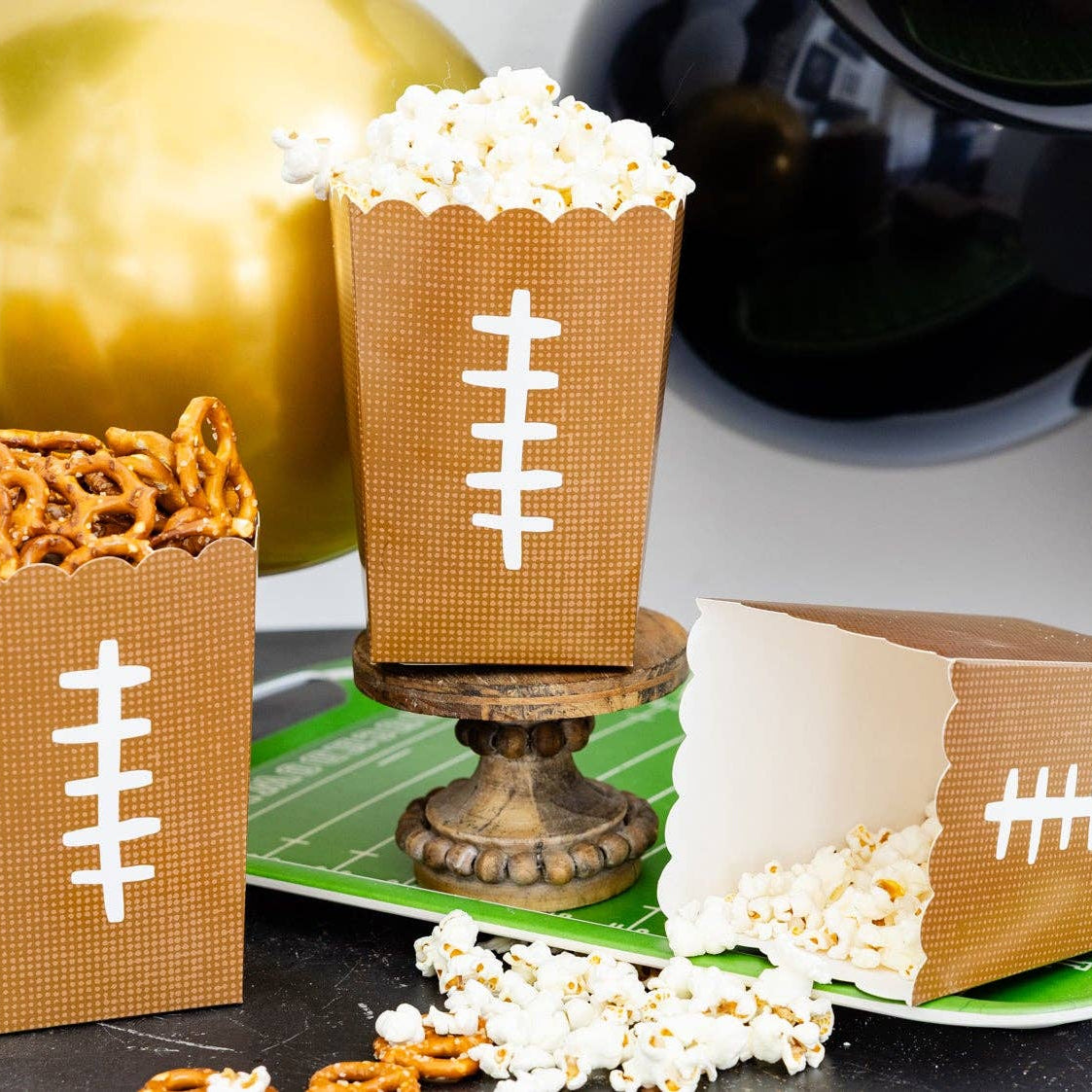 Football themed paper treat boxes filled with popcorn and snacks on a game day party table