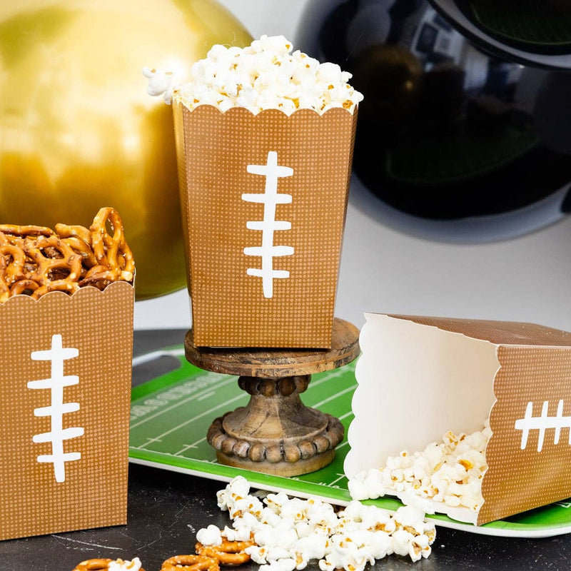 Football themed paper treat boxes filled with popcorn and snacks on a game day party table