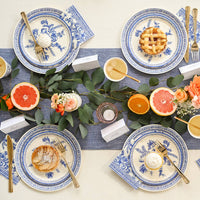 French toile plates styled on a table with citrus, greenery, and place settings