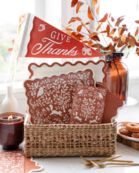 Fall buffet station featuring a basket of rust scalloped paper plates paired with a red Give Thanks pennant flag.