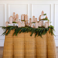 Long shot of the full holiday countdown decor village display of the assembled boxes on a rustic wicker skirted table.