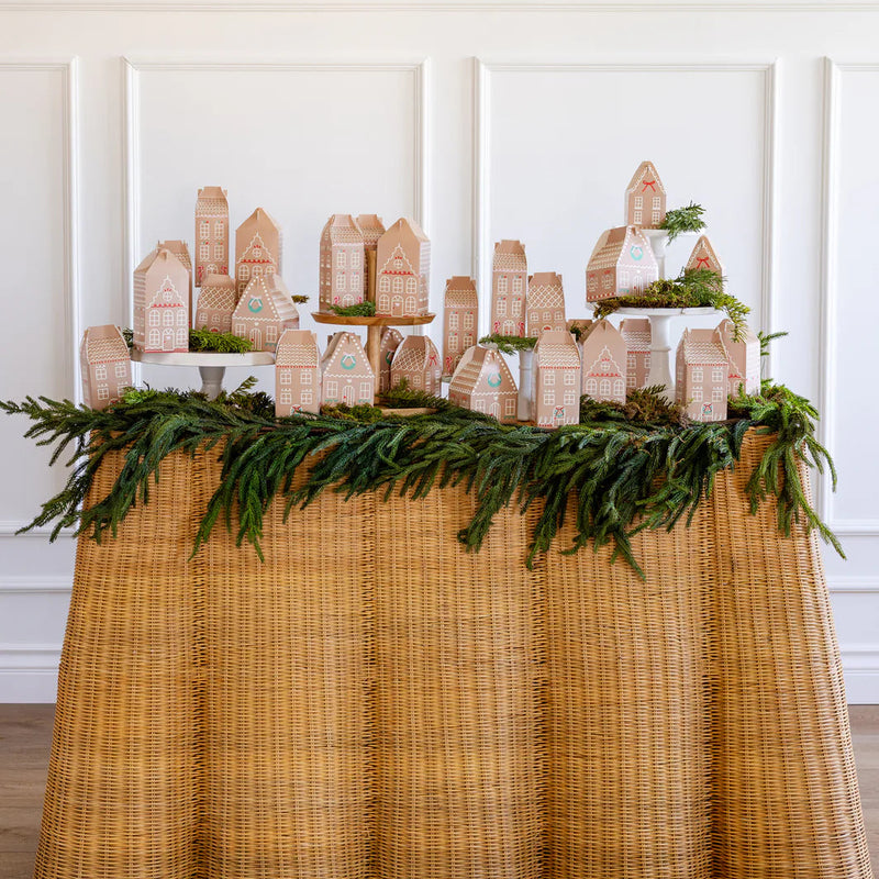 Long shot of the full holiday countdown decor village display of the assembled boxes on a rustic wicker skirted table.