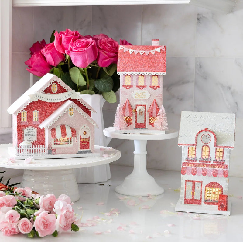 Full set of the three valentine putz house designs displayed on a marble counter with pink roses.