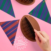 Hand attaching accordion football decoration to game time banner string