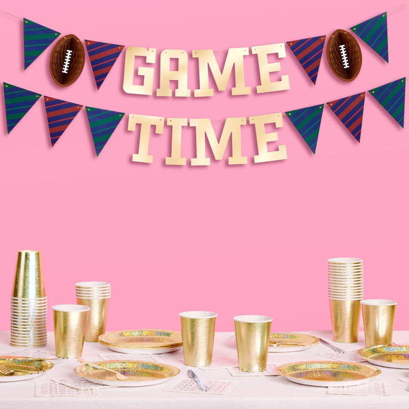 Gold foil game time banner hanging above football-themed party table with gold cups and plates