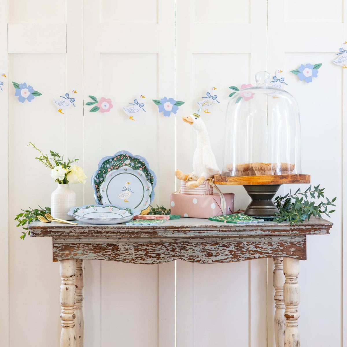 Spring party setup featuring garden goose banner, plates, and tabletop decorations