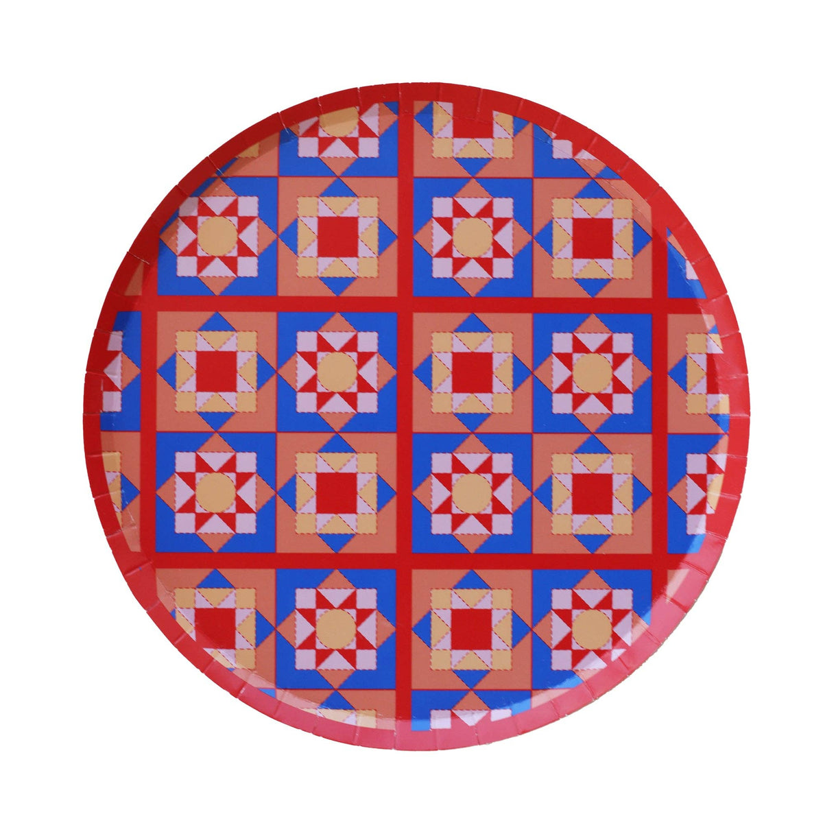 Round geometric holiday dessert plate with an all-over folk-art quilt-block pattern in red, blue, and yellow with a red rim, overhead view on white background.