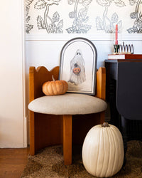 Halloween ghost tray styled in an entryway with orange and cream pumpkins, floral wallpaper and a taper candle