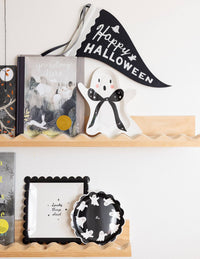 Decorative Halloween shelf featuring the ghost paper plate with other halloween figurine, books, and banner on a white wall.