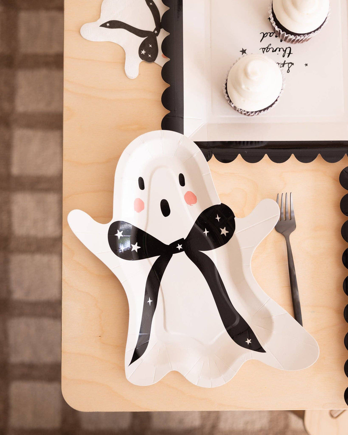 Close-up of the black and pink detail on the cream ghost plate styled with other Halloween decorations.