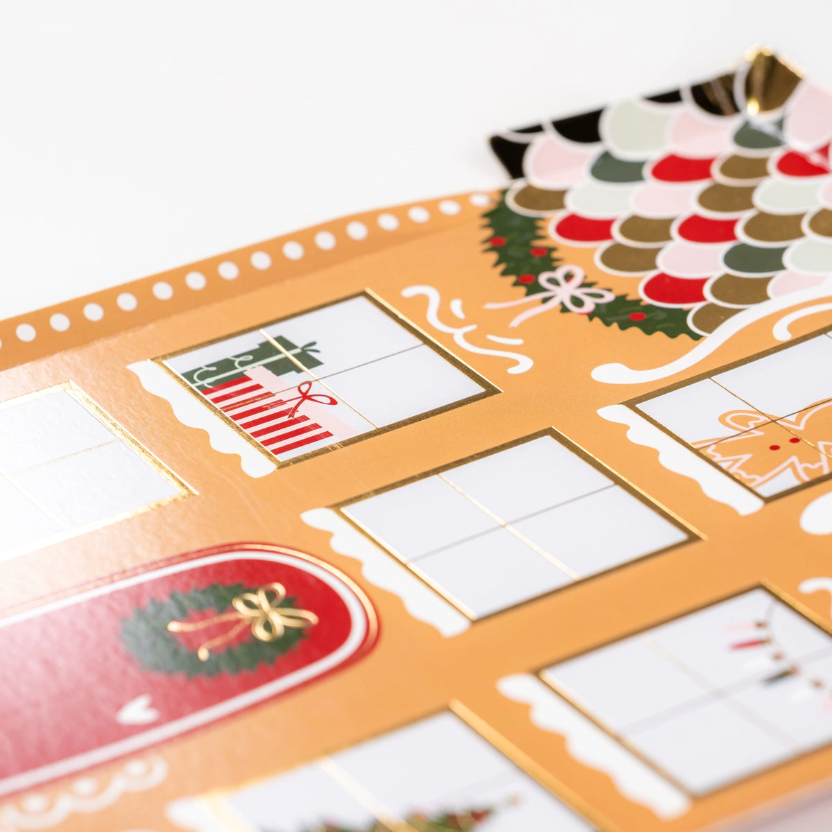 Close detail of gift-filled window with gold foil lines on gingerbread house plate.