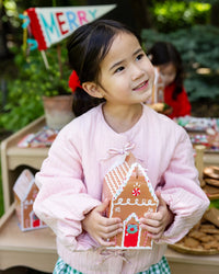 Girl holding a gingerbread house treat box at a Christmas party