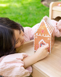 Child pressing a sticker onto a gingerbread house treat box