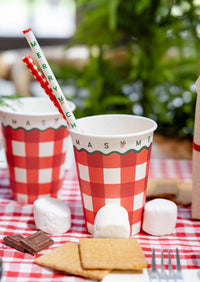 Gingham cups with red-striped straws and marshmallows against a wood backdrop.