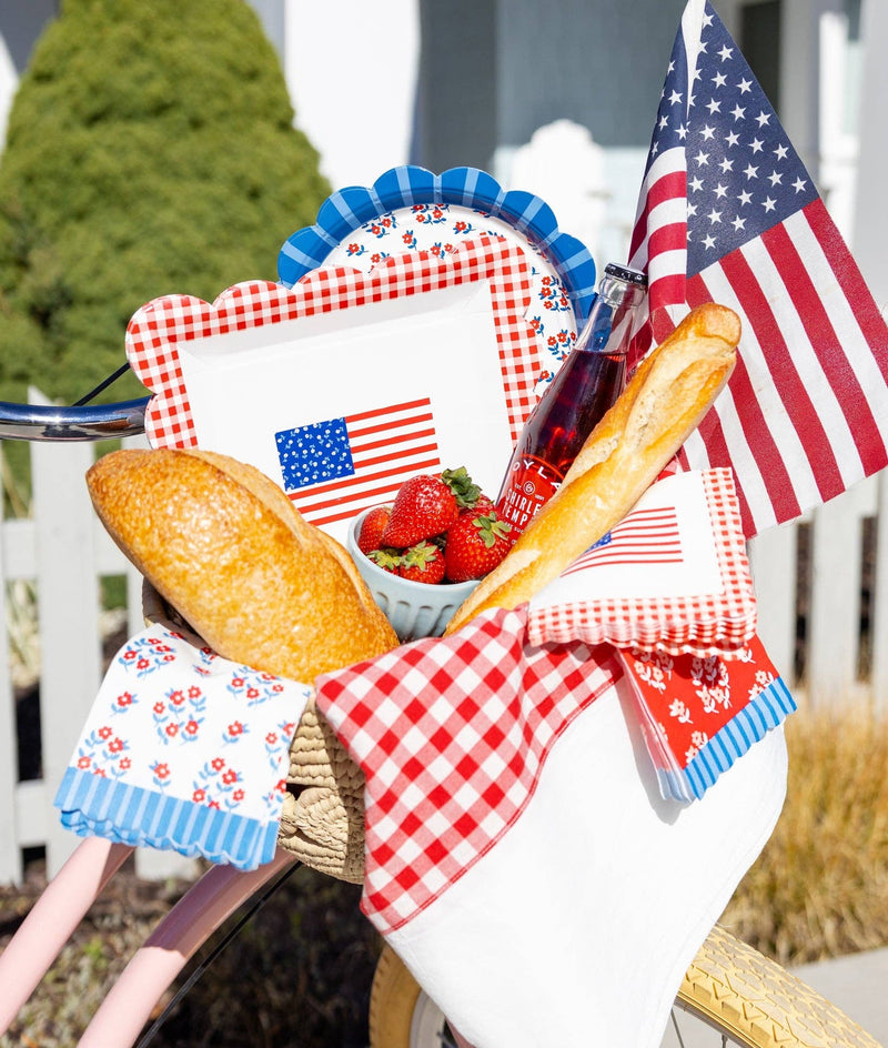 Close-up of pink bicycle basket with gingham flag plates, floral scalloped dessert plate, strawberries, and American flags
