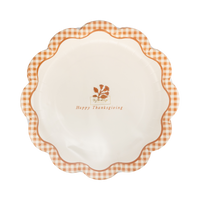 Close up detail showing glossy gold foil text and scalloped edge on rust checkered paper plate.