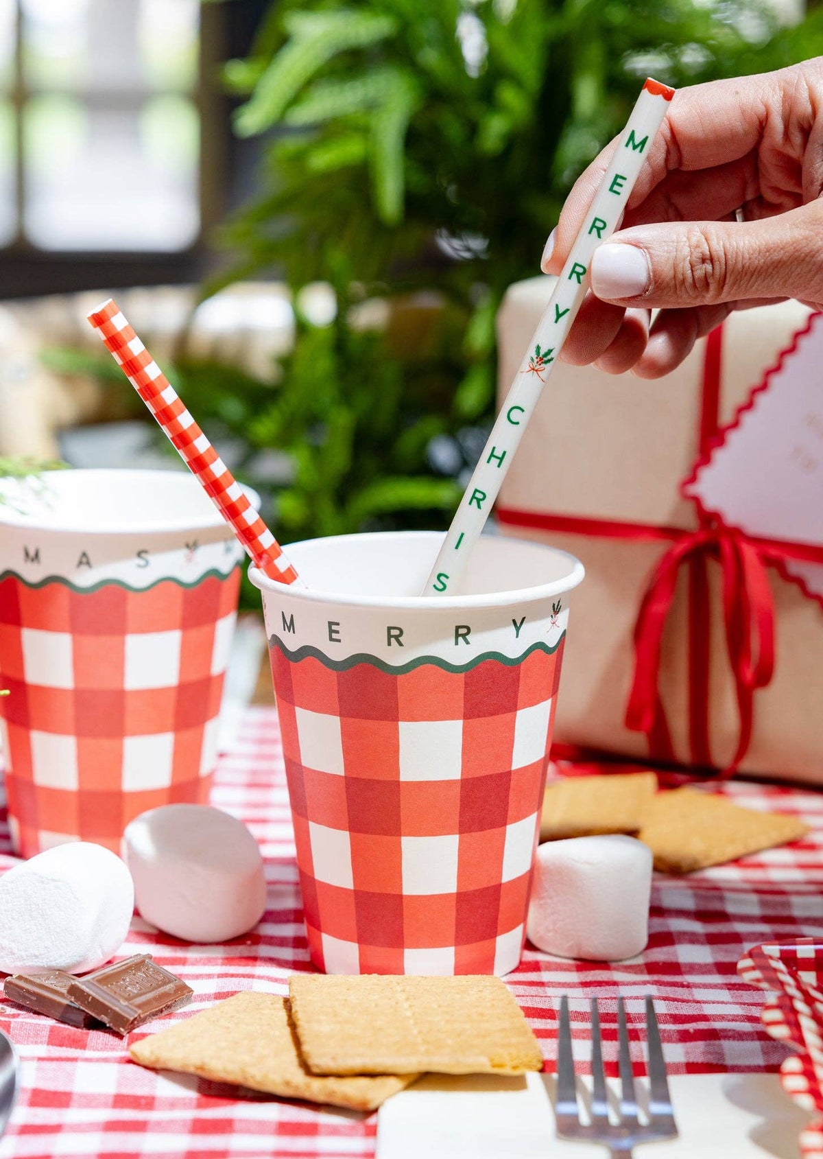 Gingham straws in red gingham party cups on a rustic table with marshmallows.