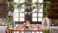 Rustic window room with a "Merry Christmas" felt banner, red gingham treat boxes on a cake stand, and a full plaid table.