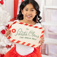 Close-up of a child presenting the Santa tag bamboo tray next to a white Christmas tree.