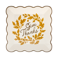 Cream paper plate with a brown "Give Thanks" wordmark and a wavy edge, front view.