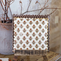Dark floral plate layered behind floral plate on a wooden display stand.
