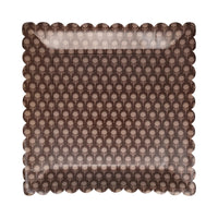 Close-up of brown plate with repeating floral motif and scalloped rim.
