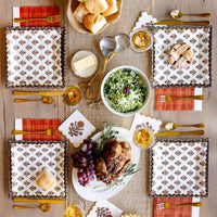 Thanksgiving tablescape with floral napkins, gold flatware, and fall dishes.