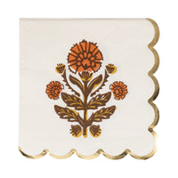 Close-up of floral artwork and metallic gold scalloped border on napkin.
