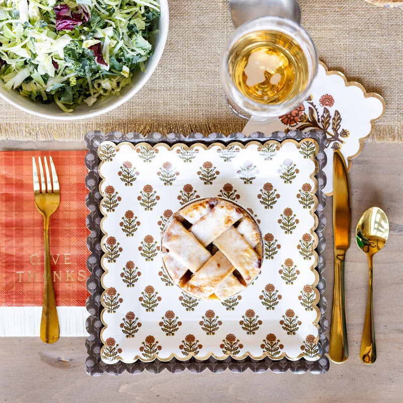 Thanksgiving tablescape featuring plaid napkin, gold flatware, and fall plates.