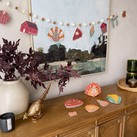 Fall harvest banner with pom poms and paper turkey, barn, pie and corn cutouts hung above a sideboard with the 3D turkey craft and its flat pieces