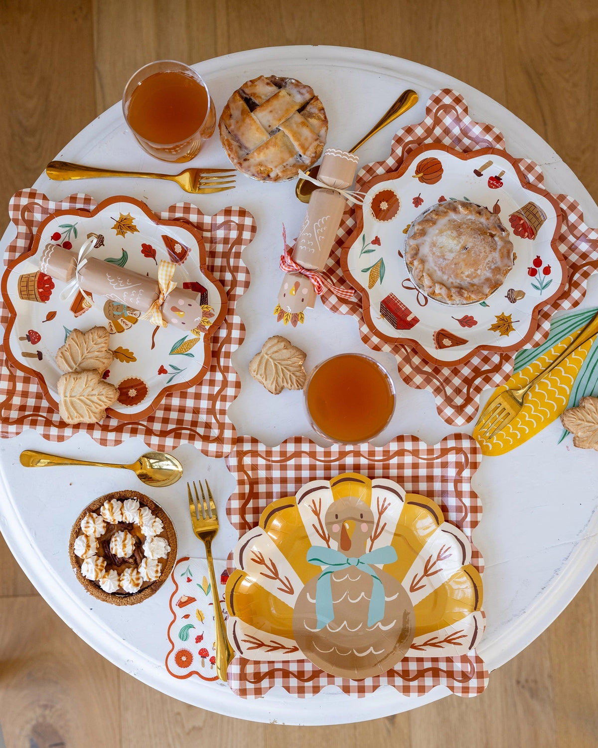 Round white table set with the Gobble Thanksgiving kit: turkey plates, harvest plates and gingham plates with turkey crackers, harvest and corn napkins and mini pies