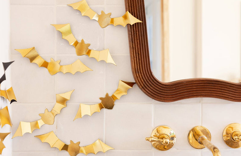 Gold bats styled beside a mirror on close up view.