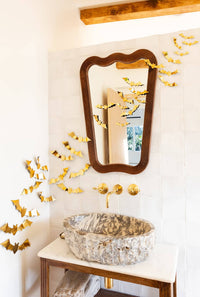 Bathroom with decorative gold bats, a mirror, and a sink.