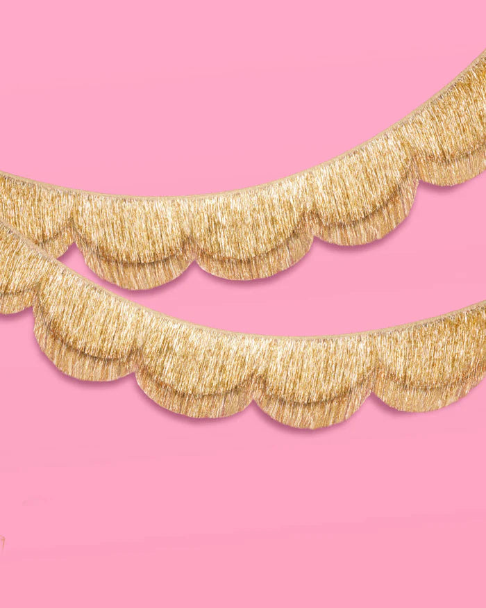 Two gold scalloped fringe banners stacked on pink background showing double-layer construction