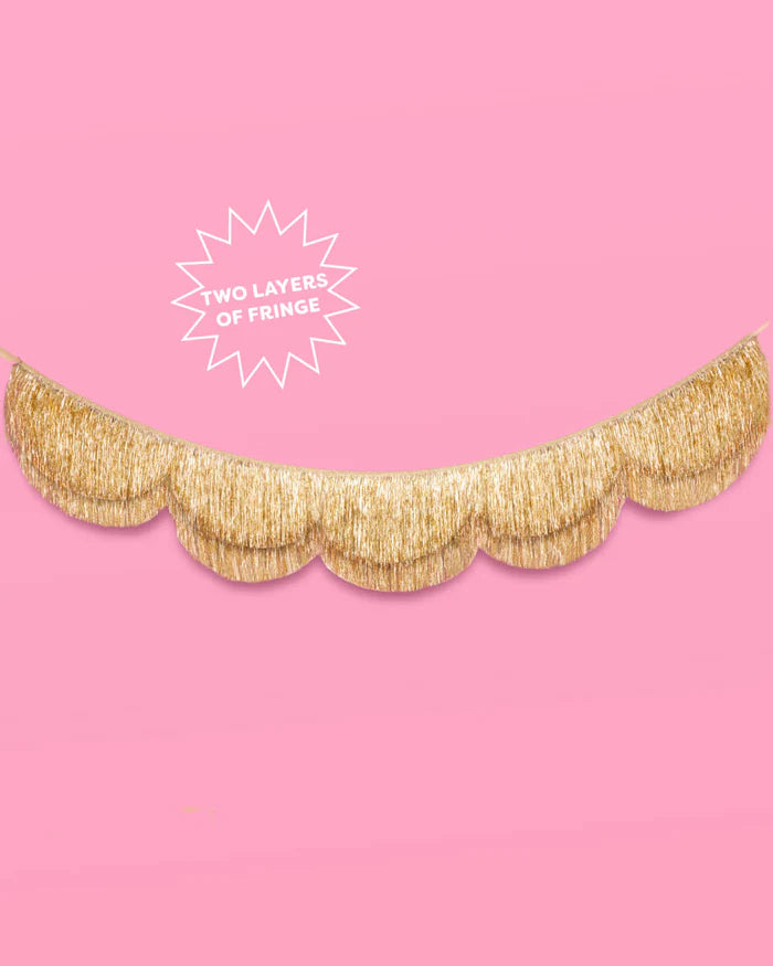 Gold scalloped fringe banner on pink background with callout reading "two layers of fringe"