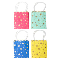 Four star-print favor bags — pink, mint, blue, and yellow — in a grid, each with gold-foil stars, a scalloped top, and white twisted-paper handles.