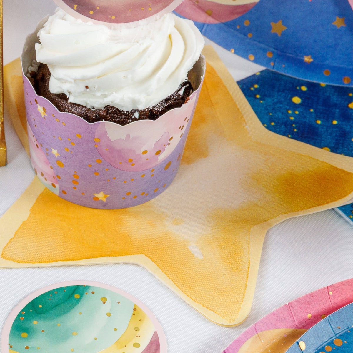 Gold star napkin under a space cupcake with galaxy plates and cups