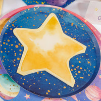 Gold star shaped napkin laid on a navy and gold galaxy plate