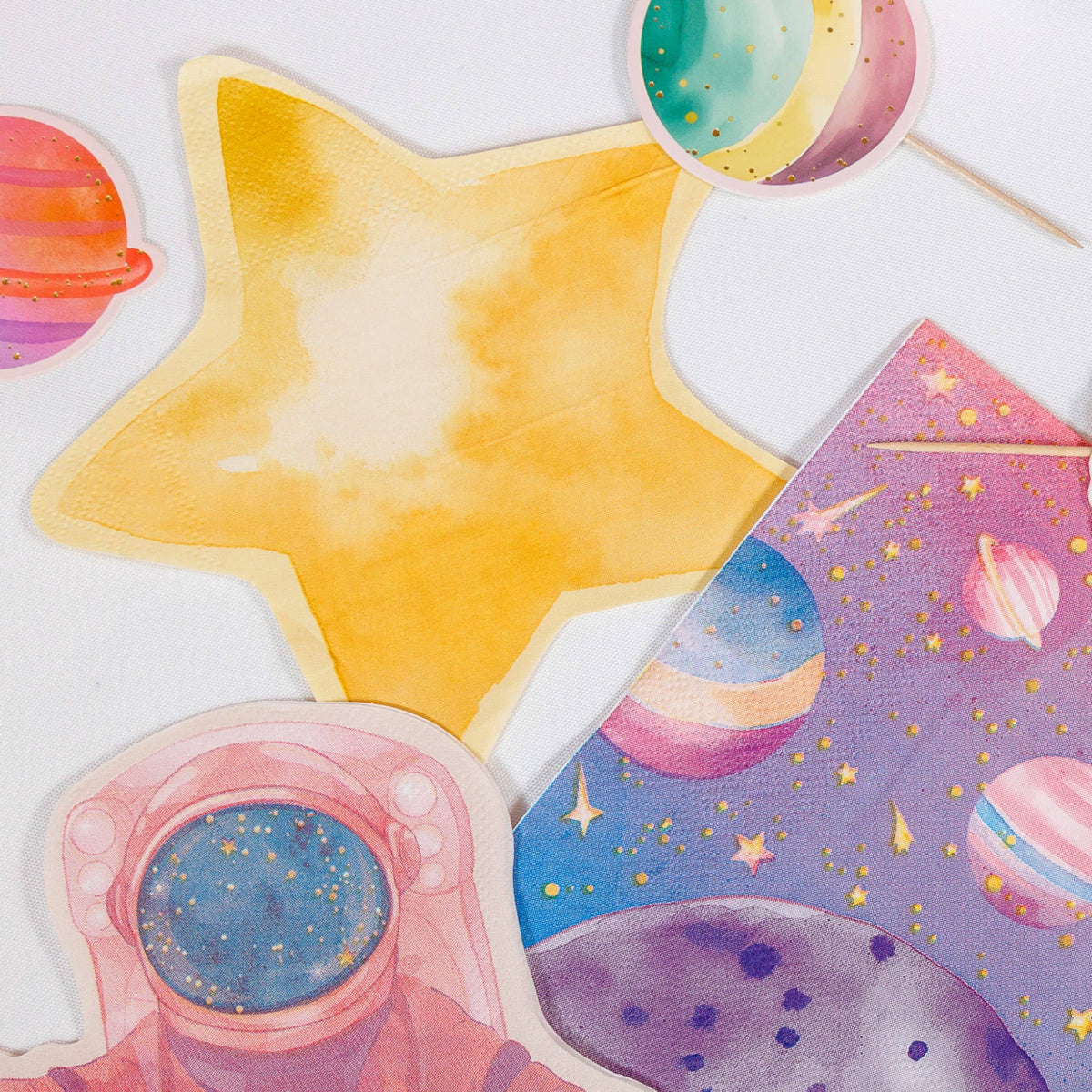 Gold star napkin with planet cutouts, an astronaut cutout and a galaxy napkin