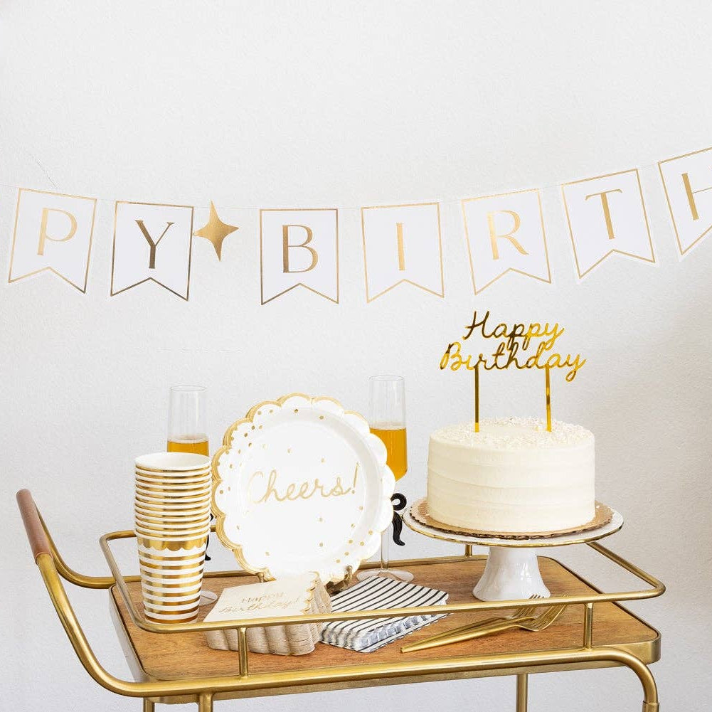 Gold birthday party bar cart with stacked gold striped 12oz party cups alongside white cake with gold Happy Birthday topper, Cheers plate and black white gold balloon garland