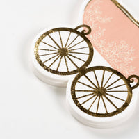 close up of gold wheel detail on baby carriage napkin
