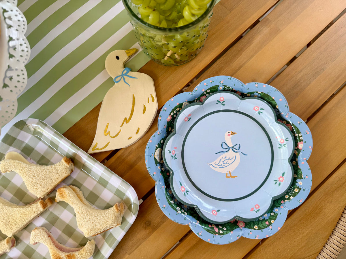 A top view of a goose themed plates, napkins, and sandwiches. 
