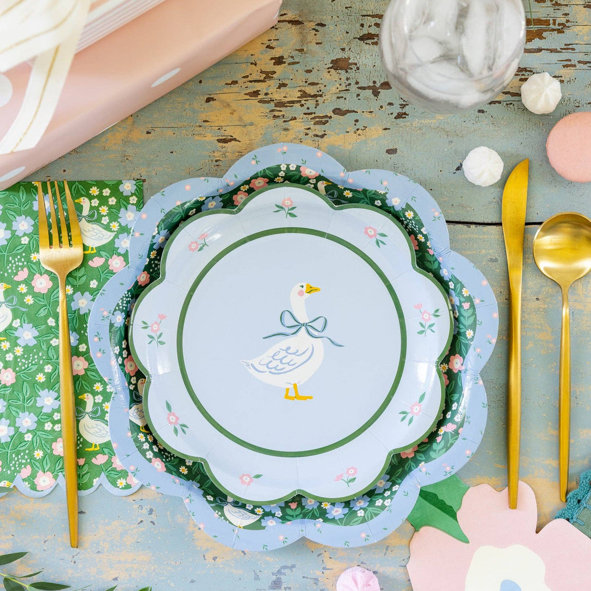 Goose pattern plates layered in a spring table setting with gold utensils