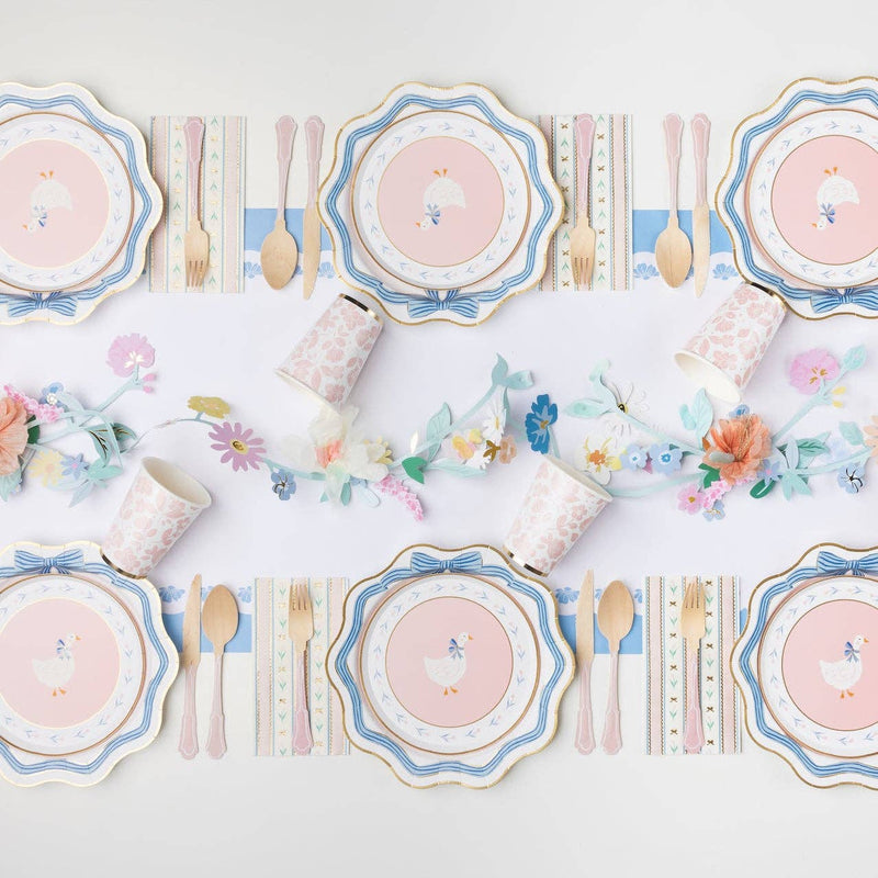 Spring party table featuring goose plates and pastel decorations.
