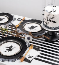 Flat lay of the gothic Halloween collection — witch plates, spider web charger, black foil guest towels, geometric elements, and black-and-white pieces.