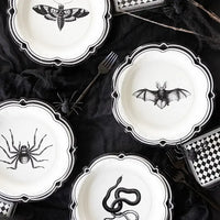 Overhead view of gothic table setting showcasing Apothecary Halloween plates, checkered napkins, and black gauze linens.