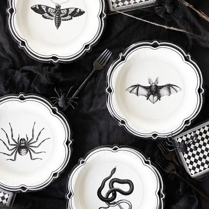 Overhead view of gothic table setting showcasing Apothecary Halloween plates, checkered napkins, and black gauze linens.
