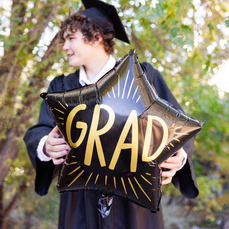 Graduate holding black star shaped grad mylar balloon during graduation celebration
