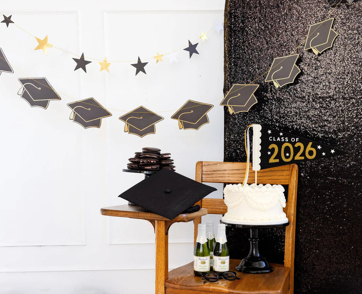 Graduation party table setup with black and gold banners, pennant, cake, and decorations